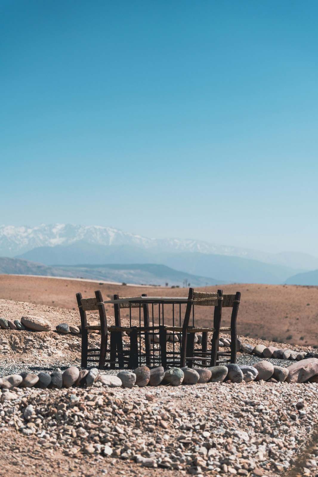 Table en bois dans le désert d'Agafay, l'Atlas enneigé au loin