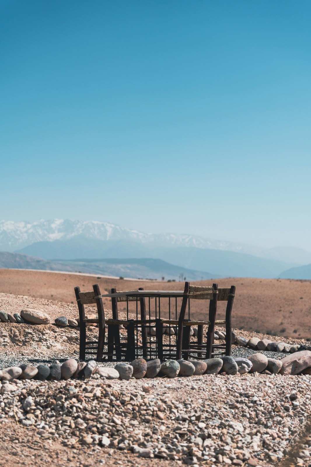 Table en bois dans le désert d'Agafay, l'Atlas enneigé au loin