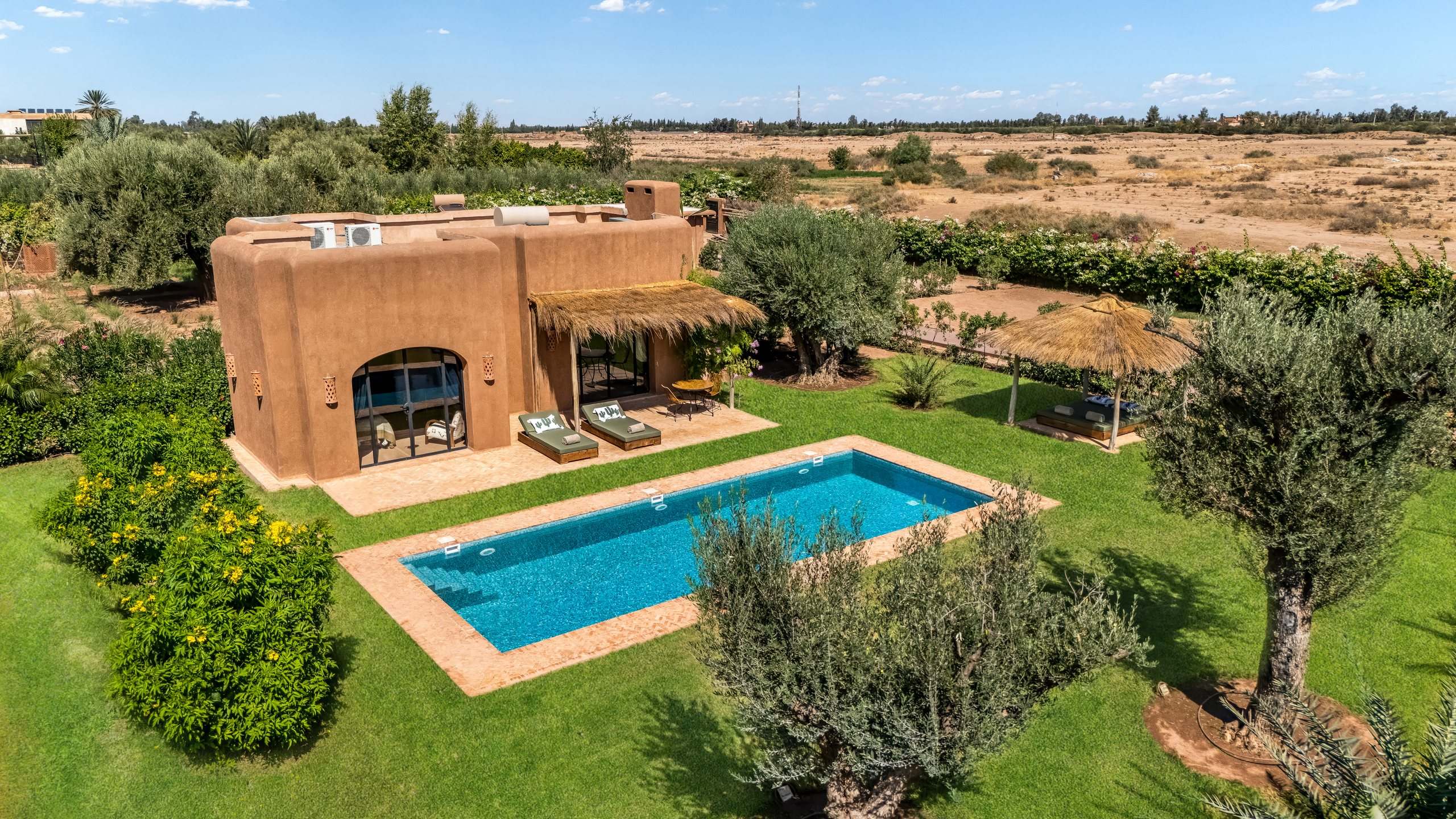 Un lodge et sa piscine au milieu des oliviers, vu du ciel